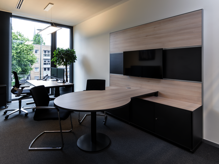 Sitz-Steh-Tisch WINEA PRO Beraterplatz und WINEA MAXX Scheibentürenschrank mit einem Besprechungstisch