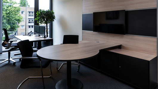 Sitz-Steh-Tisch WINEA PRO Beraterplatz und WINEA MAXX Scheibentürenschrank mit einem Besprechungstisch