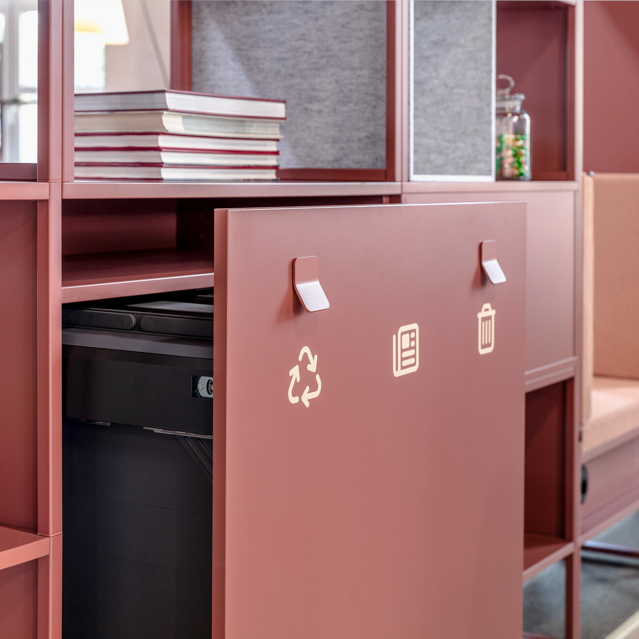 Detail einer Mittelzonen-Lounge mit rostroten, raumgestaltenden WINEA MAXX Regalen und integriertem Mülltrennsystem. WINI Forum Sandsteinhalle, Ausstellung zur Hausmesse 2025