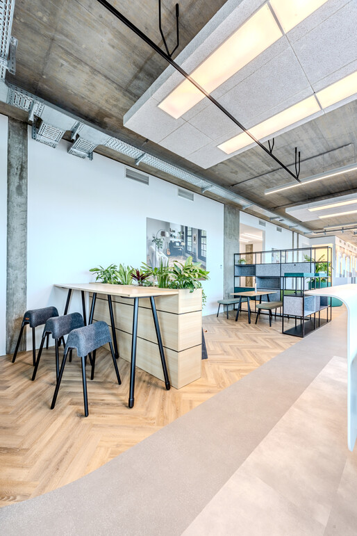 WINEA TEAMS Stehtisch mit WINEA FLEX UP Stehhocker, WINEA ELEMENTS mit Pflanzaufsatz und WINEA MAXX REGALE. Davor WINEA TEAMS Tisch auf Sitzhöhe mit Sitzbänken.