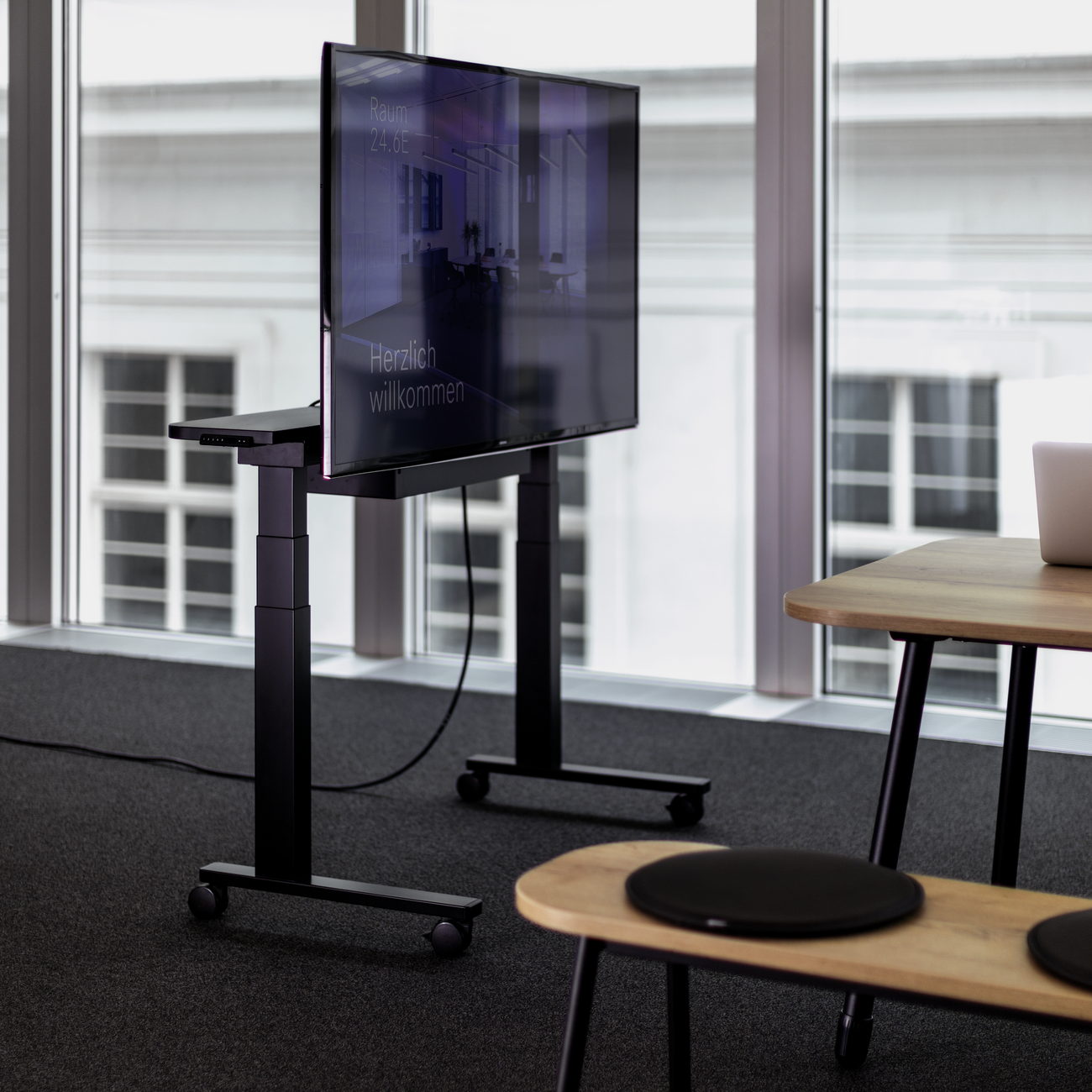 Mobiles, elektromotorisch höhenverstellbares WINEA STARTUP 2.0 TV-Mobil für Monitore mit bis zu 90 Zoll Bildschirmdiagonale.